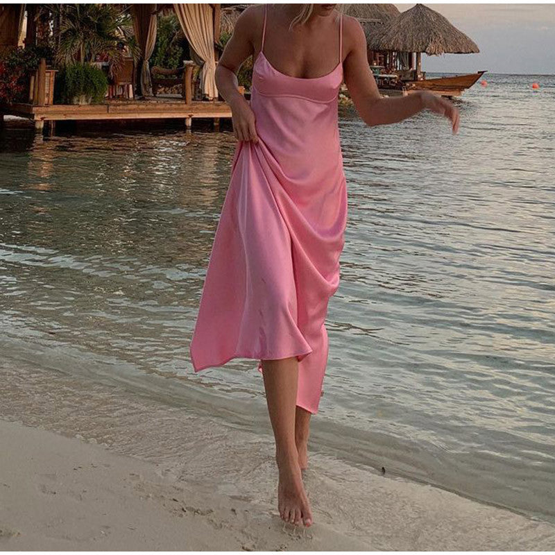 a woman in a pink dress walking on the beach