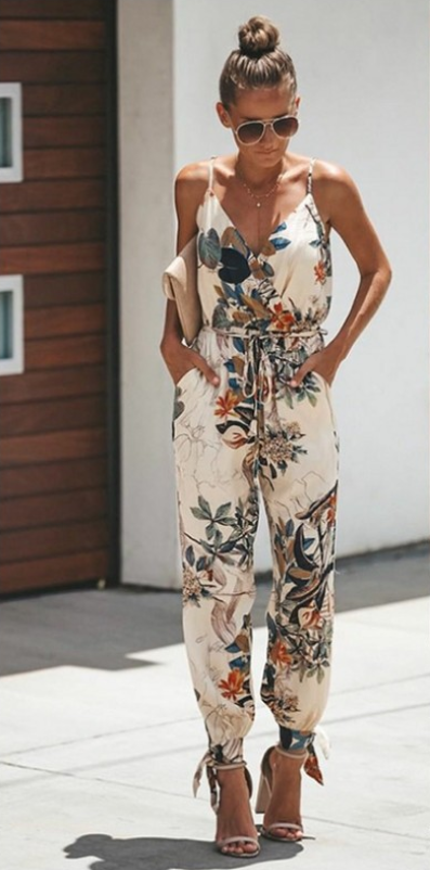 a woman standing on a sidewalk wearing a floral jumpsuit