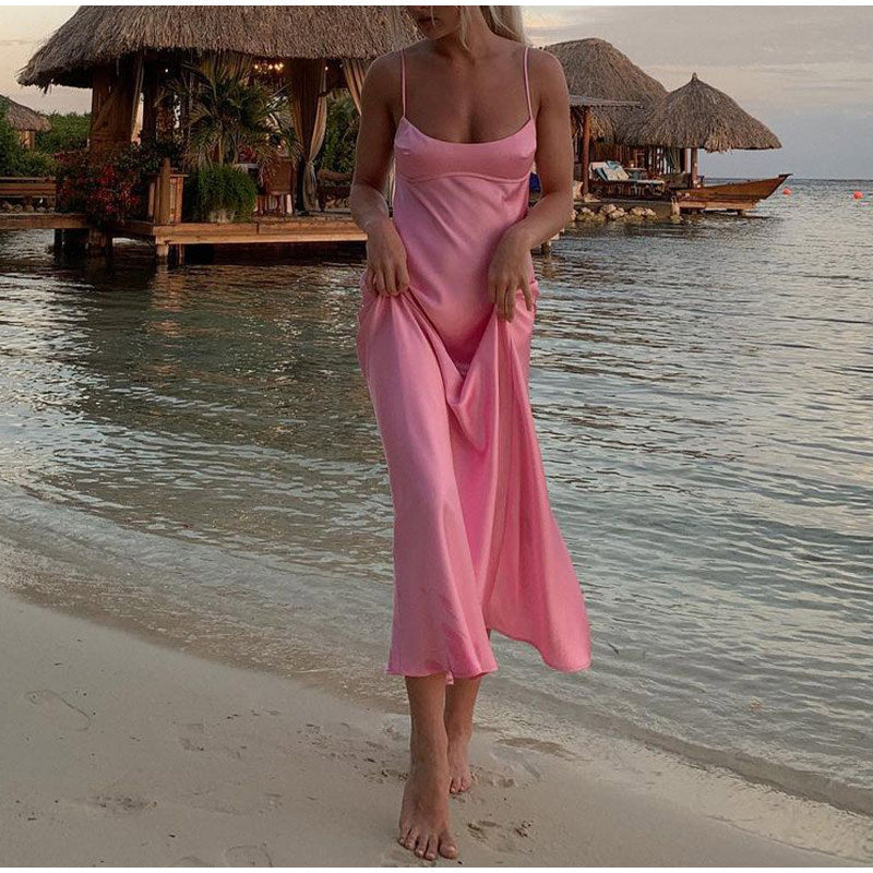 a woman in a pink dress standing on a beach